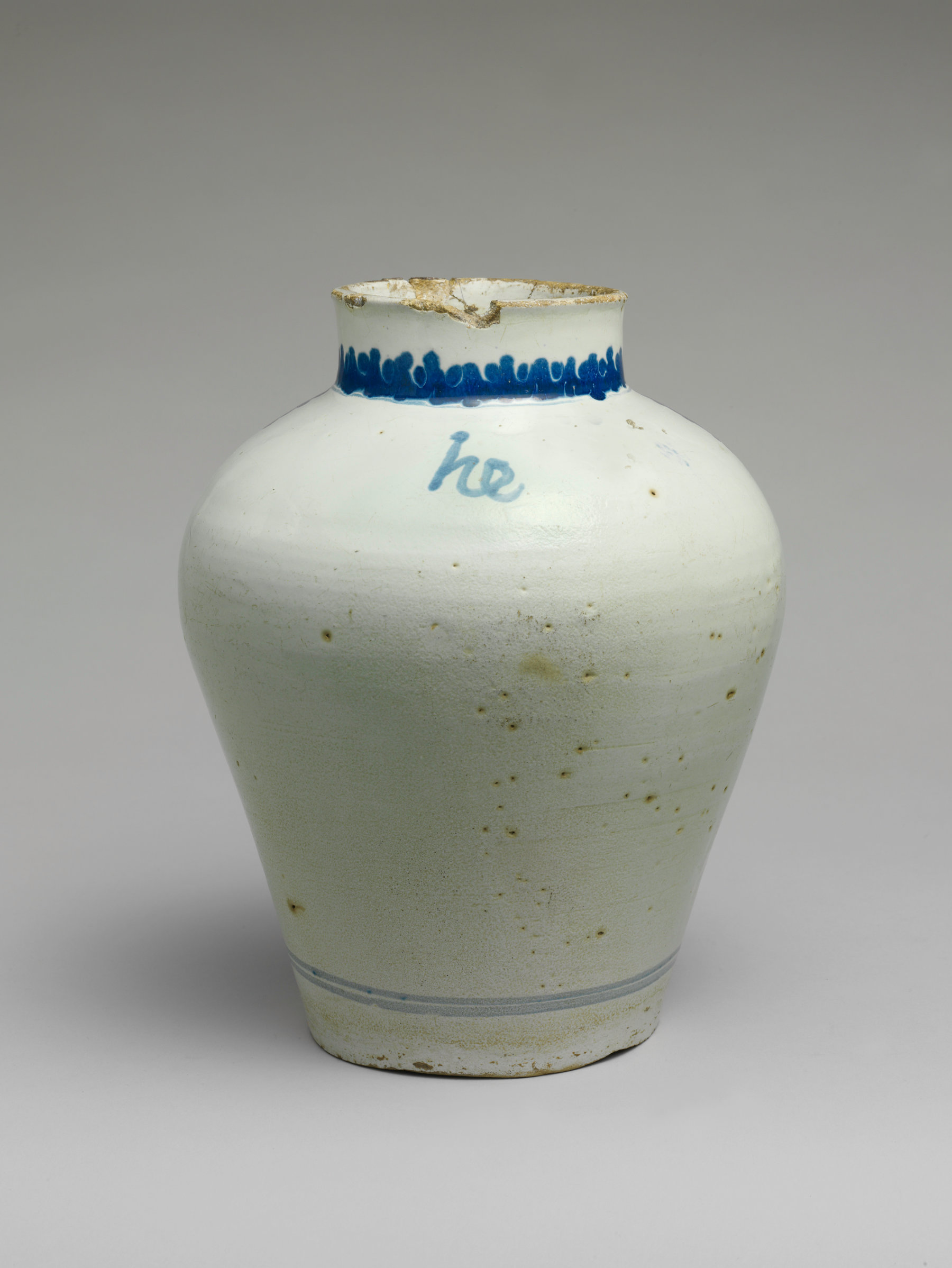 A cream bulbous vessel with minimal blue decoration at top and a mark that resembles he.