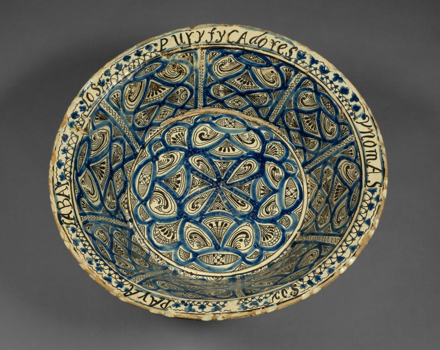 A cream bowl decorated with black and blue curving lines, with text around the outer edge.
