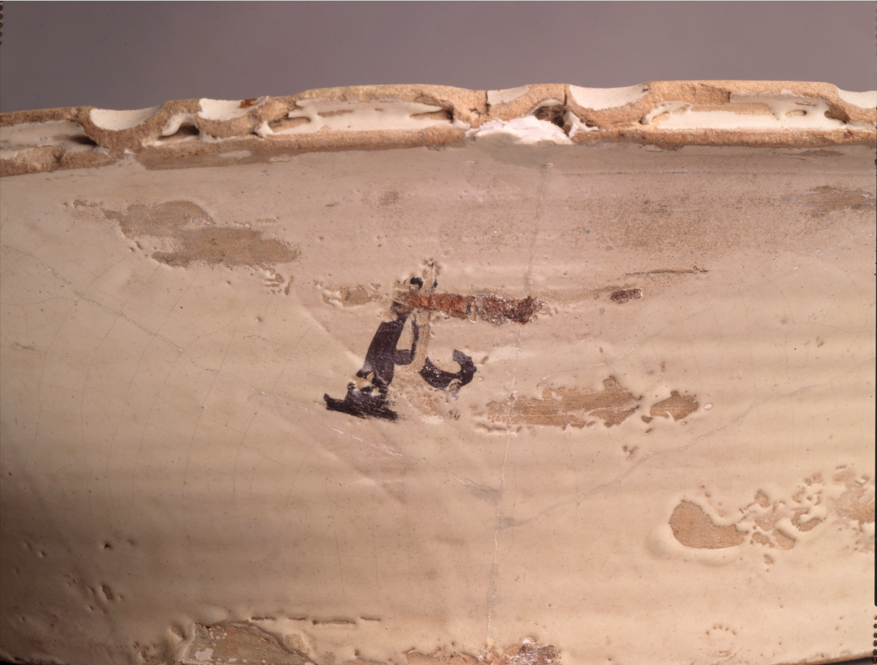 A close-up view of a cream vessel marked with a black symbol.