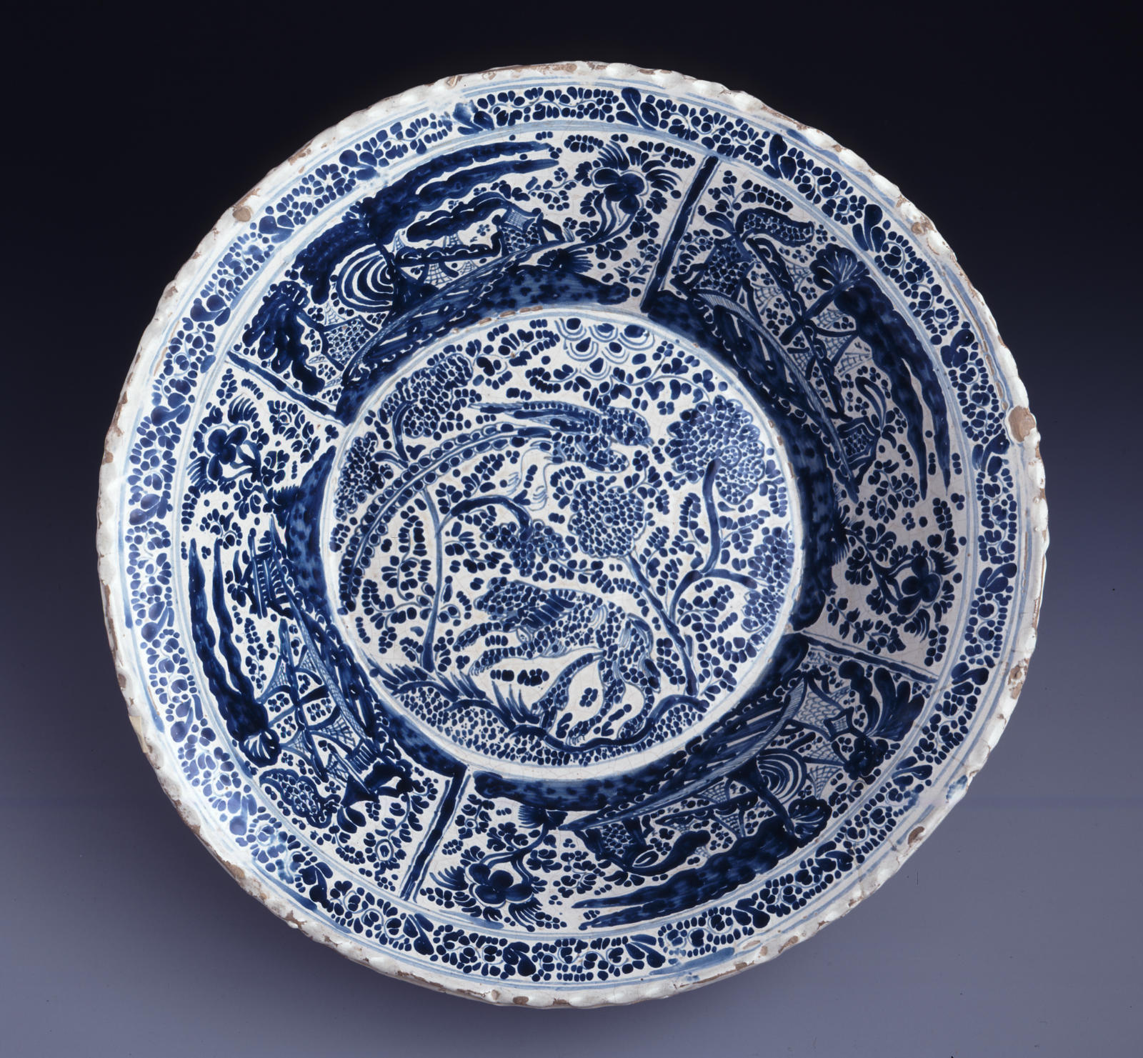 A white plate or bowl heavily decorated with blue animals and vegetation motifs.