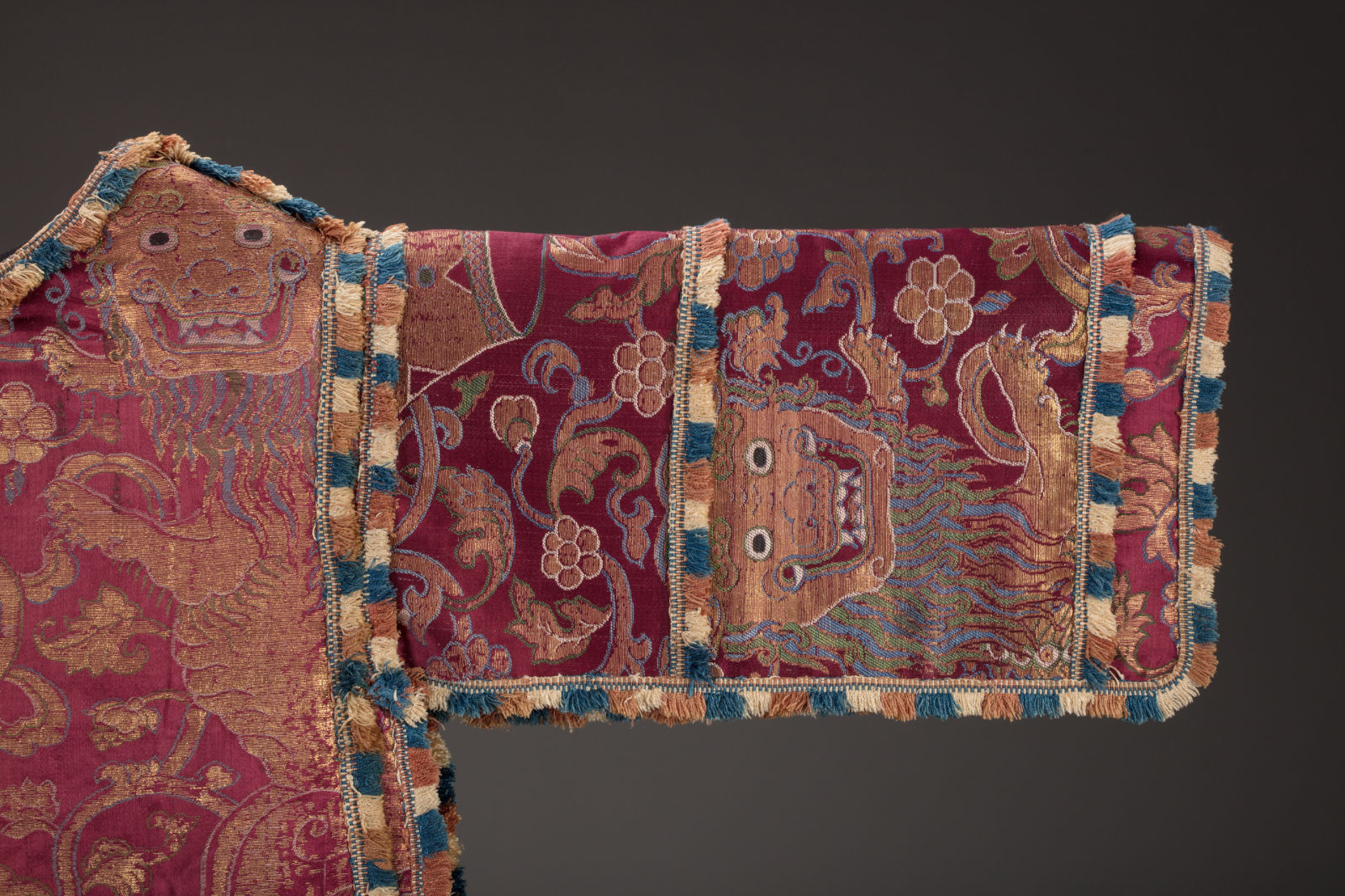 A close-up view of the sleeve of a garment decorated with lion and floral motifs.