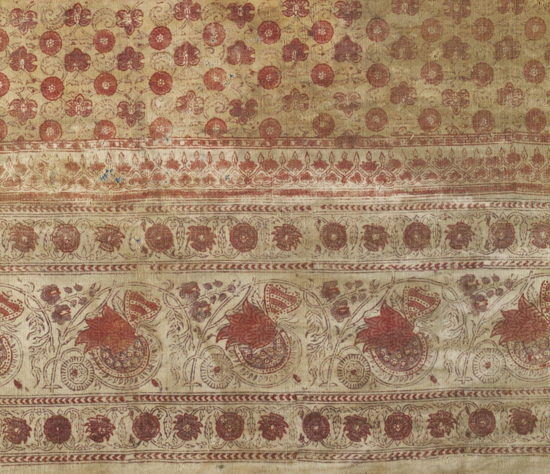Two textiles (one blue and one cream, both with red floral motifs) against a blue background with a typed white card.