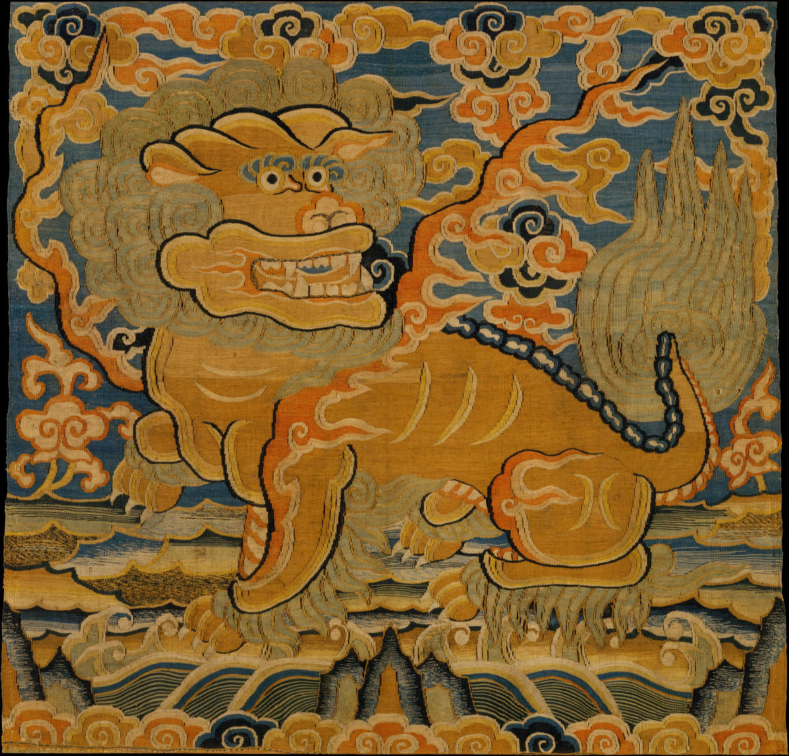 A textile featuring a yellow lion or dragon against a blue sky embellished with stylized orange and yellow abstract shapes.