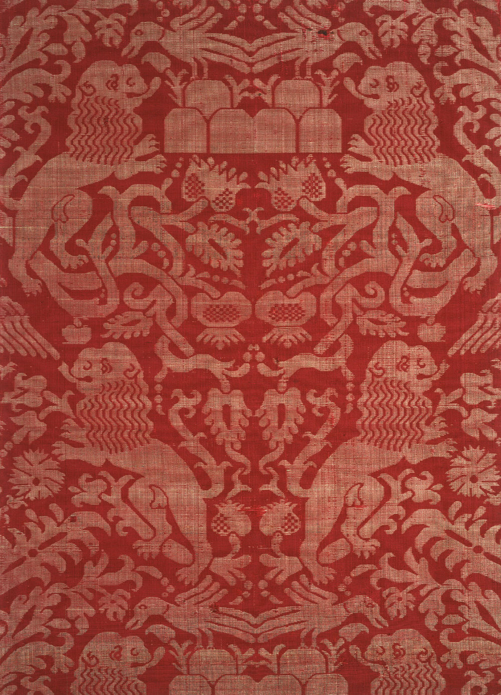 A close-up view of a red textile featuring pale animals (birds and likely lions) and floral motifs.