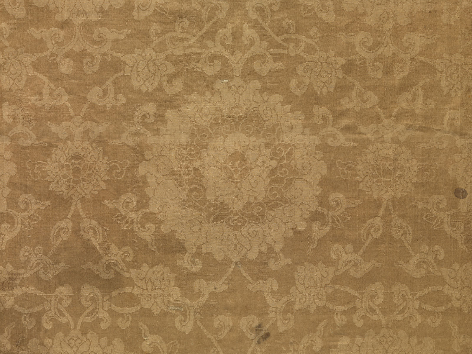 A close-up view of pale brown cloth with light-colored floral motifs throughout.