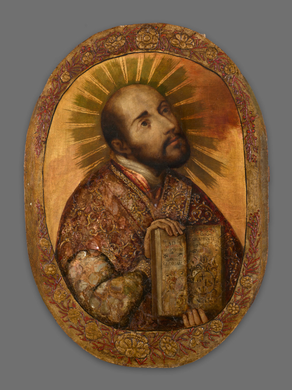 A bearded man holds an open book and looks to the upper right against a gold background, which features painted rays emitting from his head.