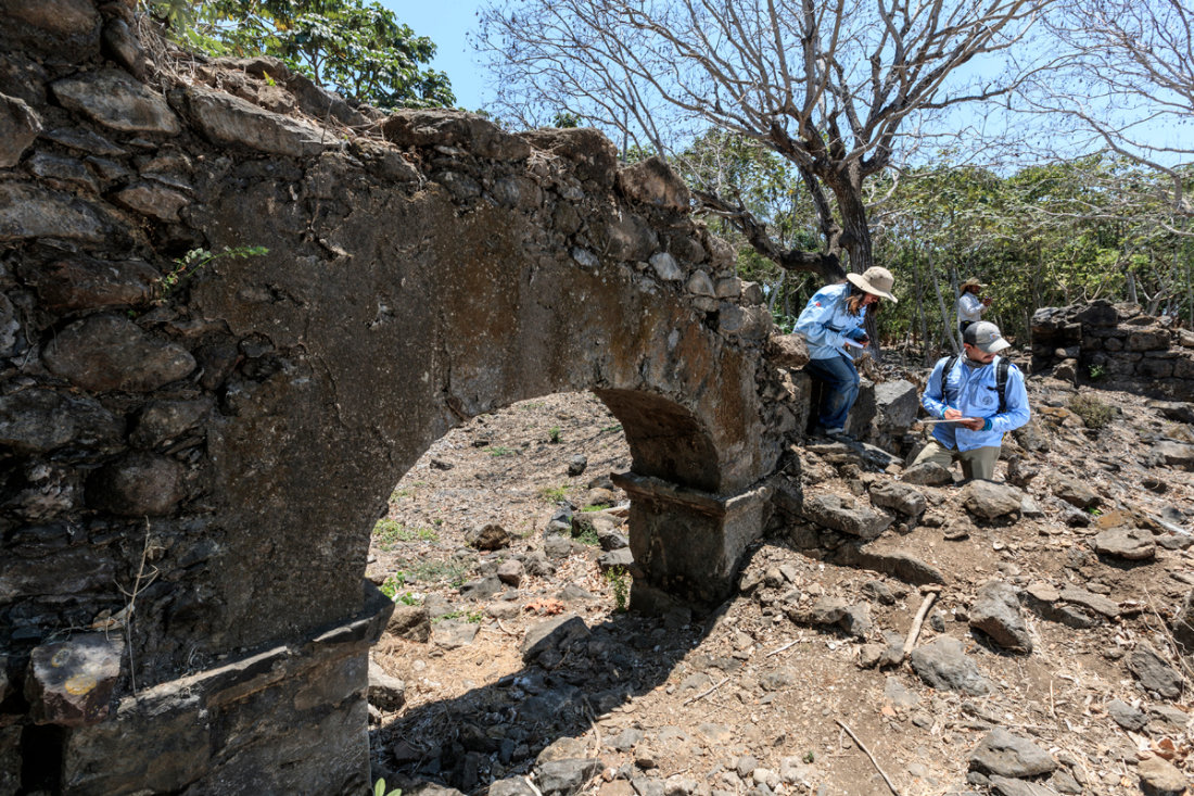 Two people take notes near a stone arch.