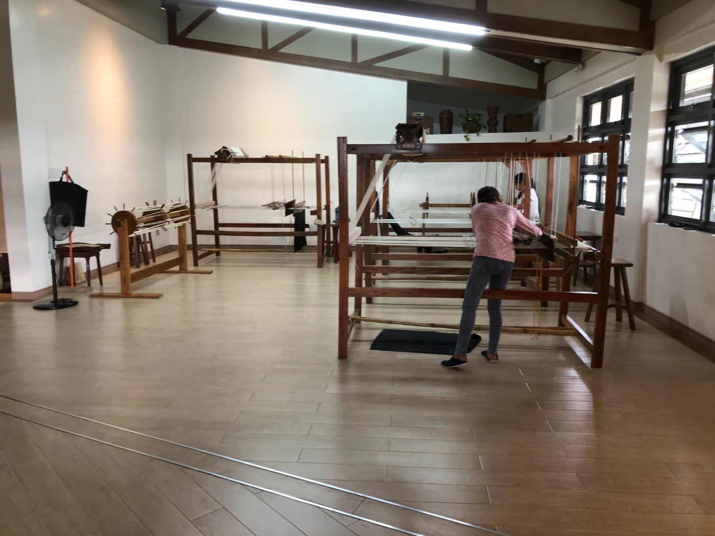A photograph of a woman working at a wooden loom.