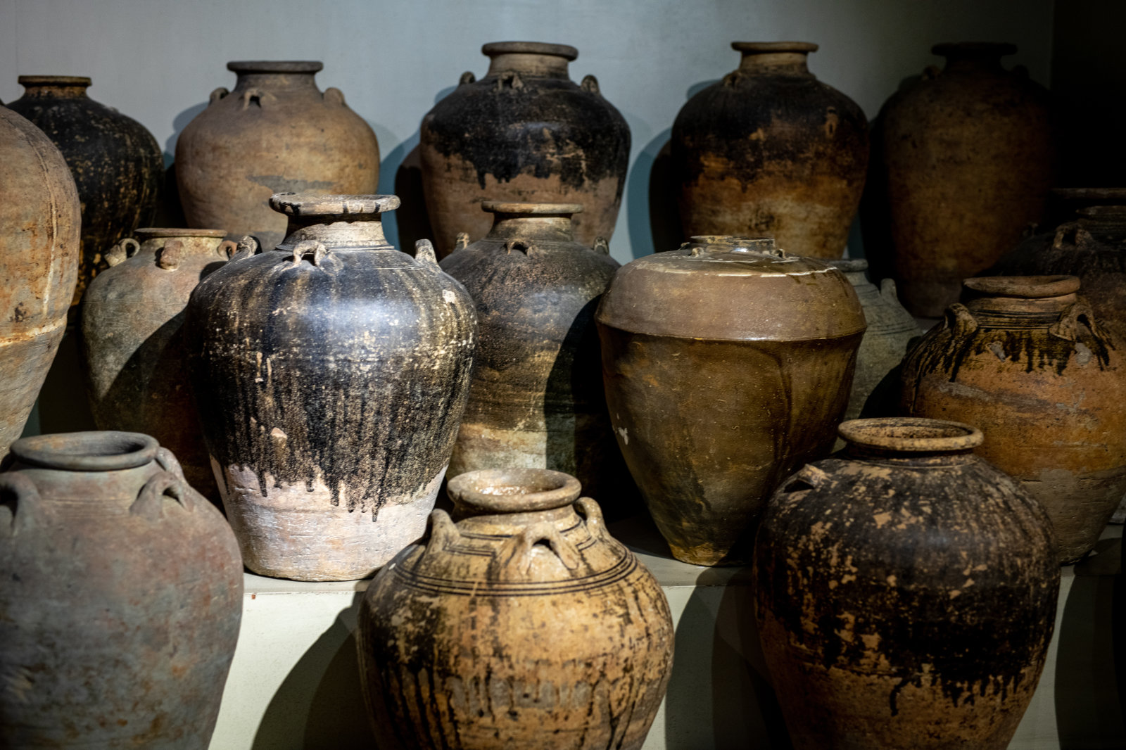 Fifteen earthenware vessels displayed on three tiers.