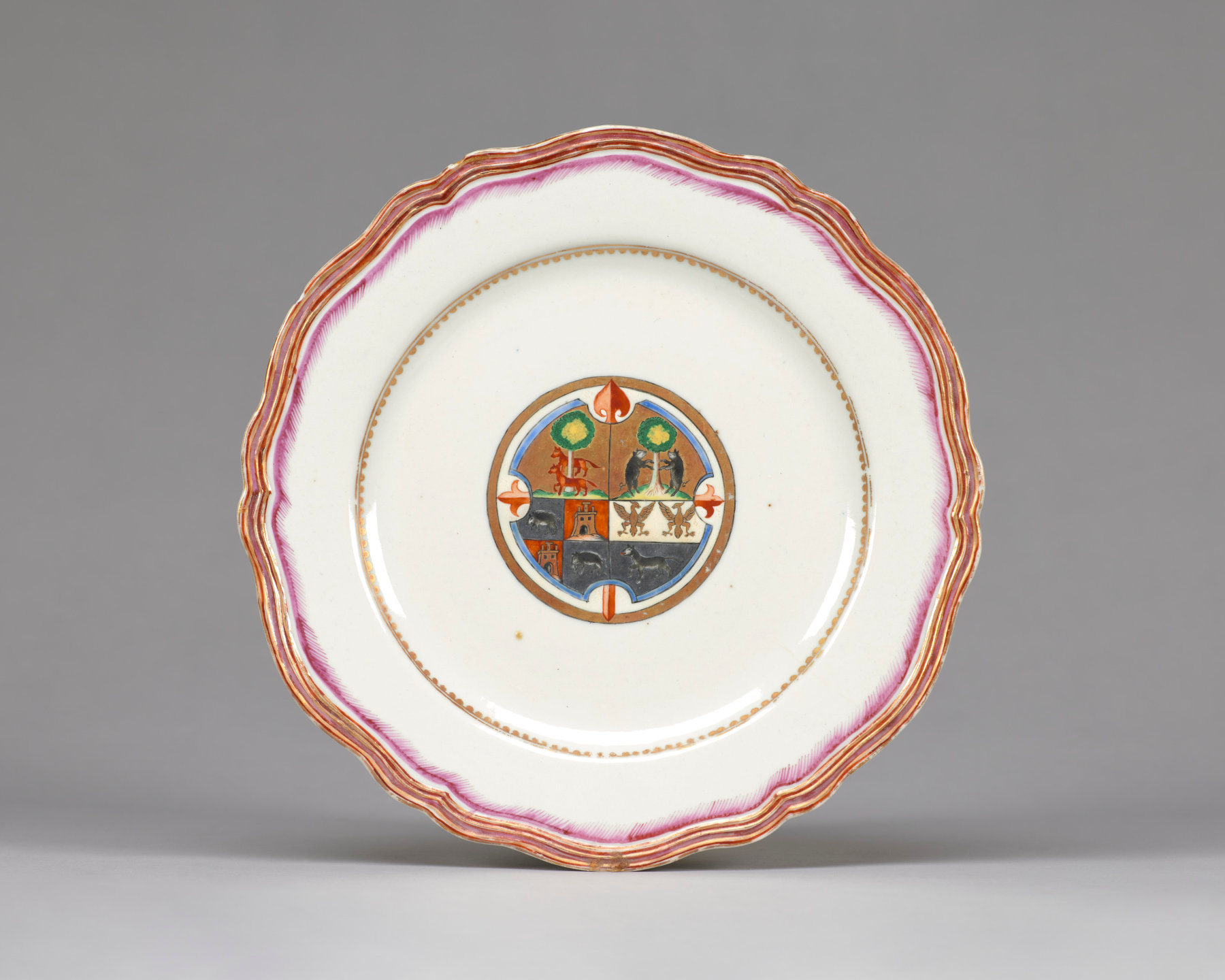 This white plate with a red border features images of animals, buildings, and trees in the center.
