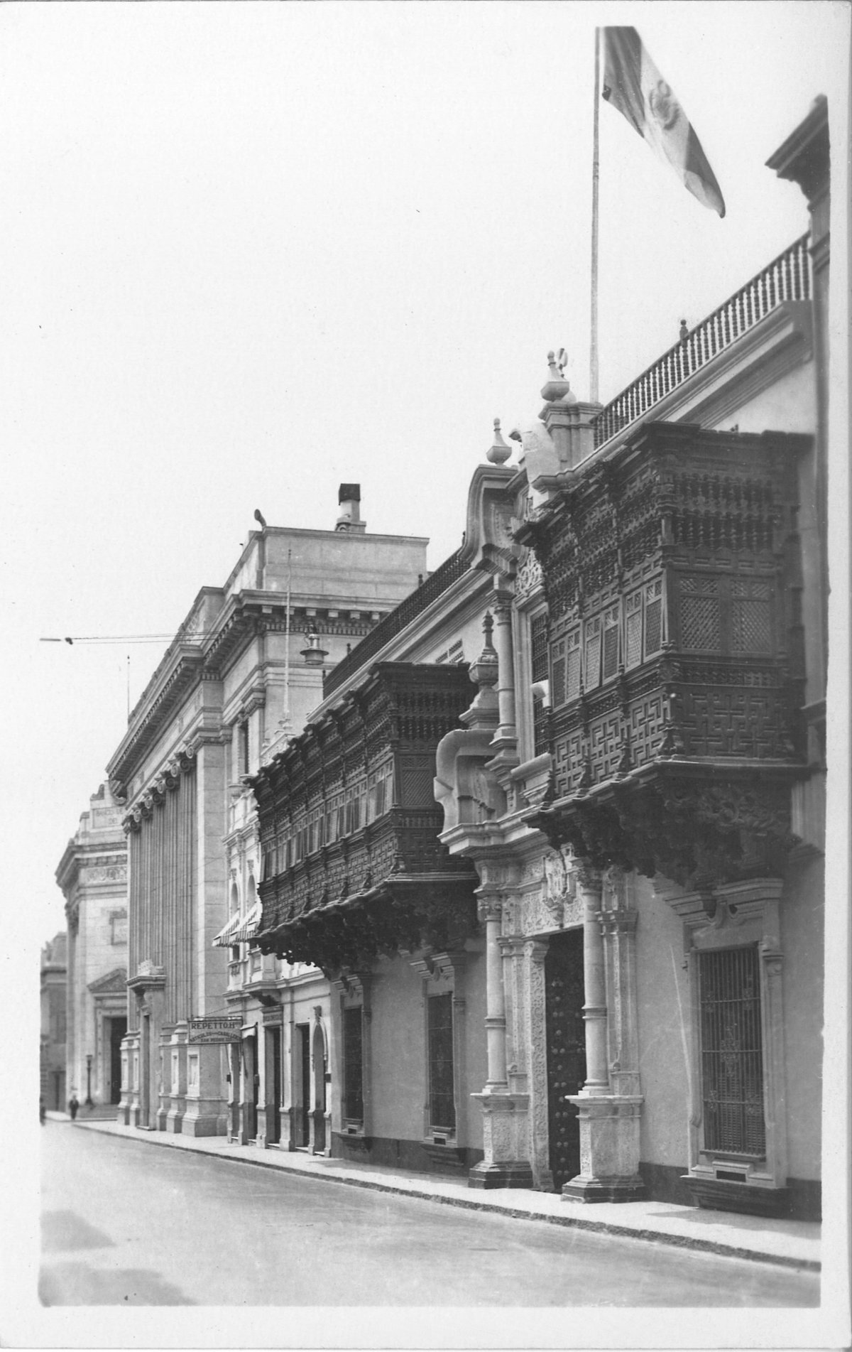 A black-and-white photograph of a row of buildings receding into the background.