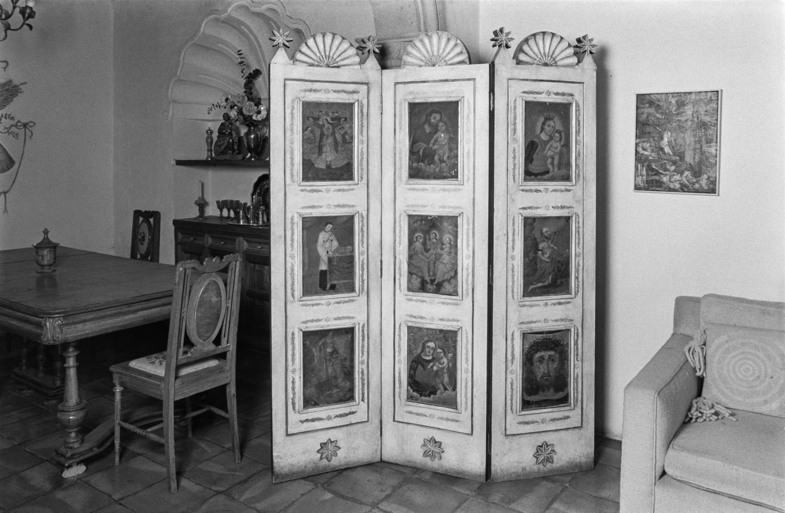 A black and white photograph of a 3 panel biombo with 9 rectangular vignettes of religious scenes.