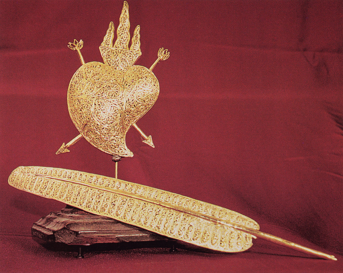 A gold wirework heart and quill.